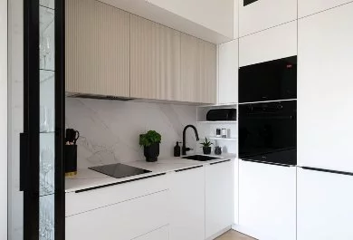 Nowoczesna kuchnia z białymi szafkami, czarnym zlewem i pionowymi frezami na frontach