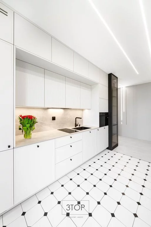 Widok na kuchnię z ryflowanymi frontami i geometryczną podłogą w bieli i czerni