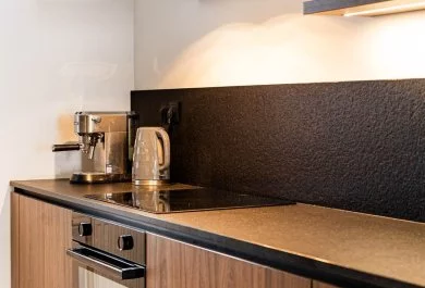 Strefa gotowania z piekarnikiem, czarnym okapem i drewnianą zabudową dolną.