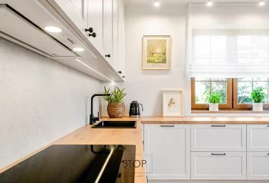 Klasyczne białe meble kuchenne z drewnianymi blatami i czarnym AGD