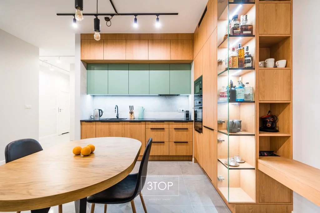 Drewniana kuchnia narożna z zielonymi frontami kuchennymi