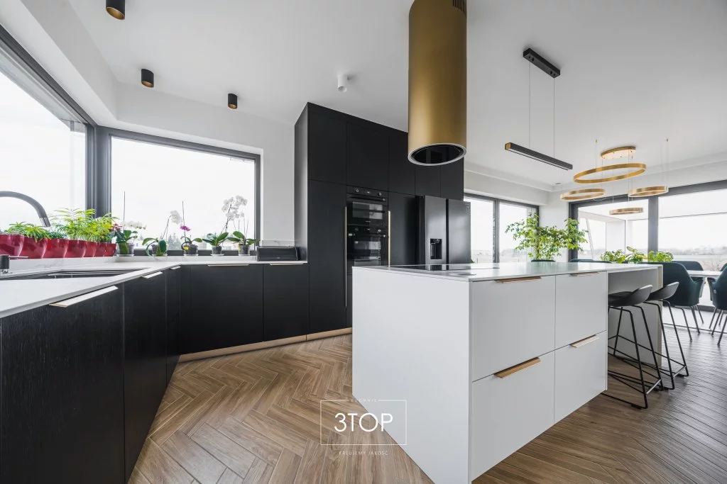 Czarna kuchnia glamour z biała wyspą i złotymi elementami dekoracyjnymi